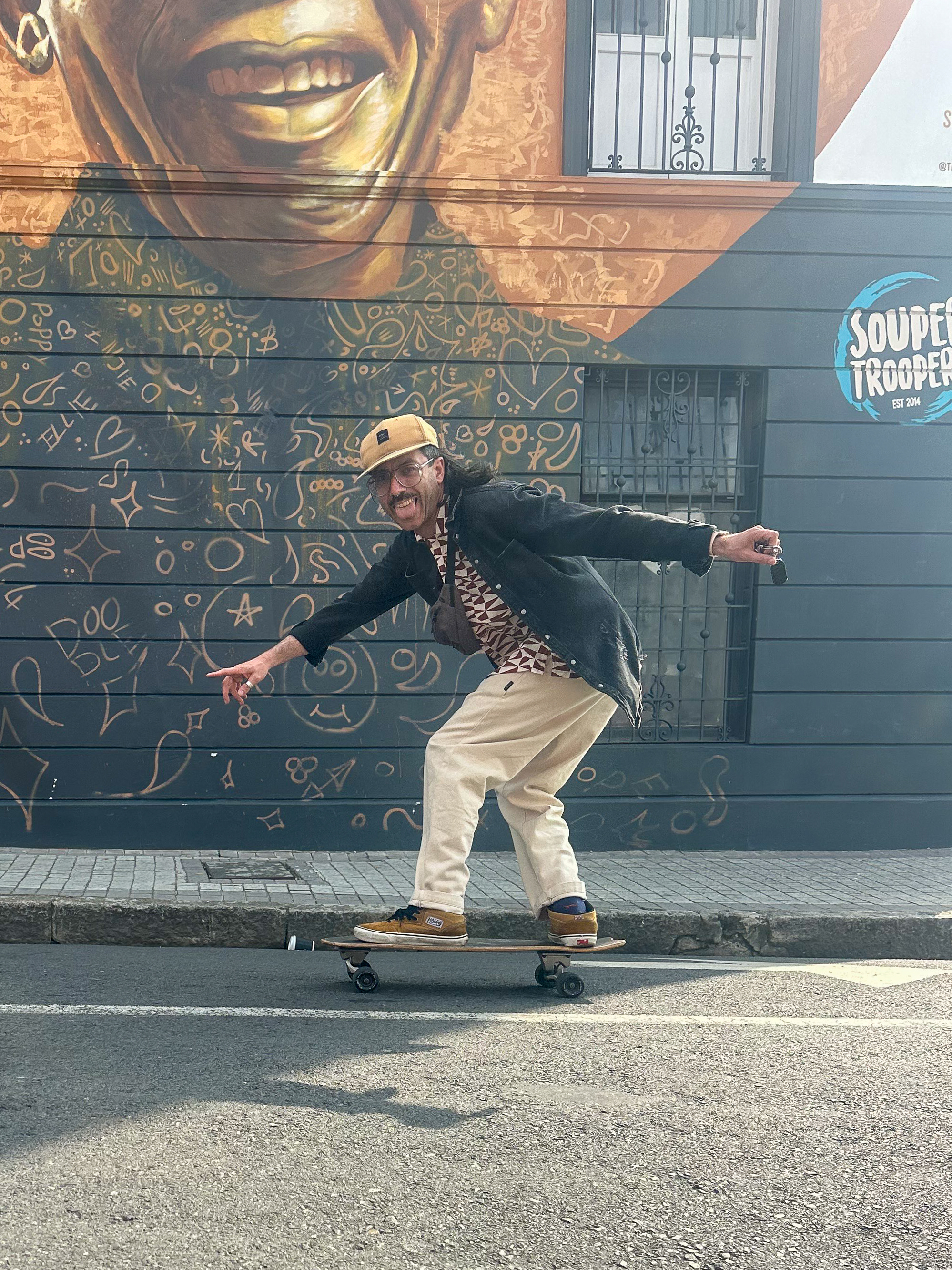 Tour guide skateboarding in front of colourful street art mural in Cape Town
