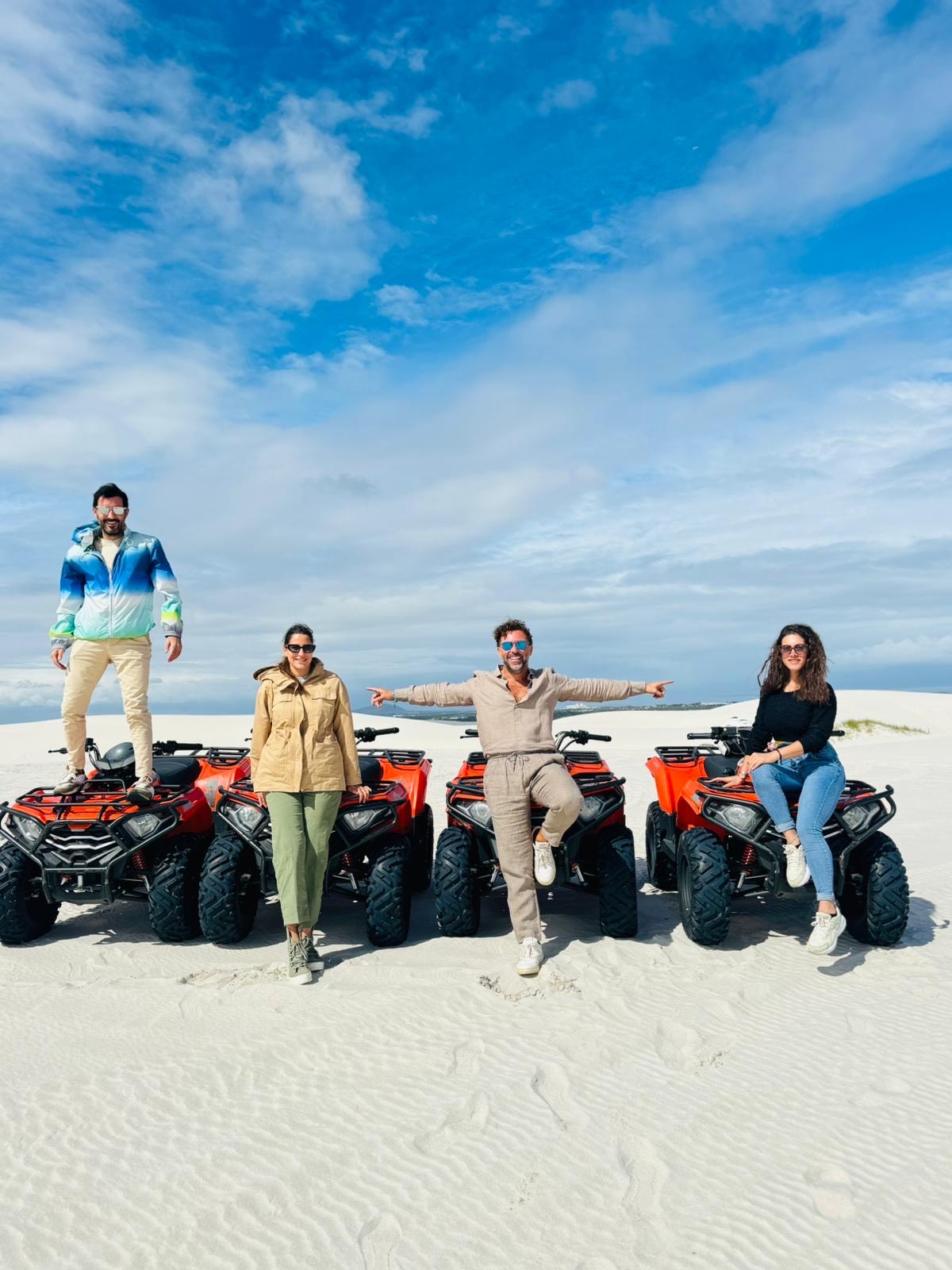 Smiling quad bikers posing with raised hands during an adventure in Atlantis Dunes, Cape Town.